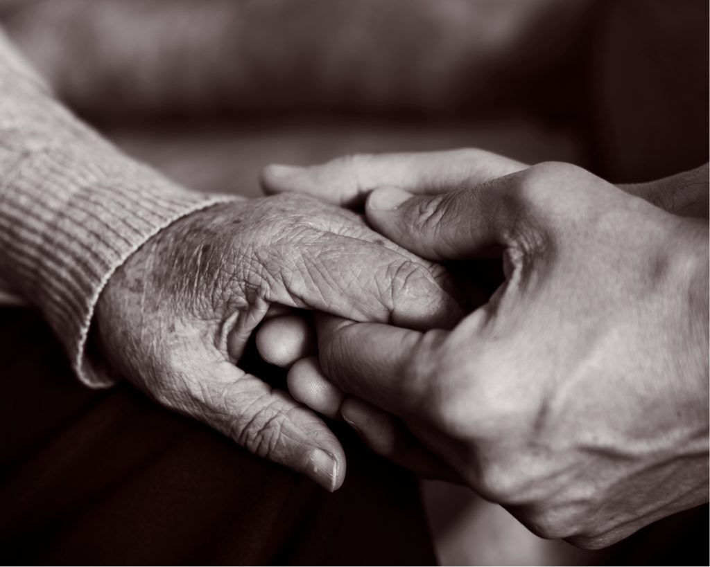 Nahaufnahme der Hände eines jungen Mannes, der liebevoll die Hand einer alten Frau hält. | Schwarz-Weiß | AdobeStock #198181514